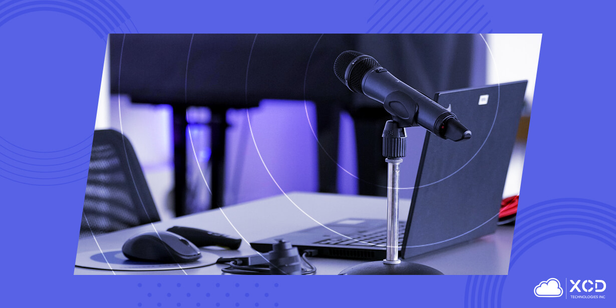 Microphone on a stand beside an open laptop and computer mouse on a desk, representing event management logistics and live event coordination.